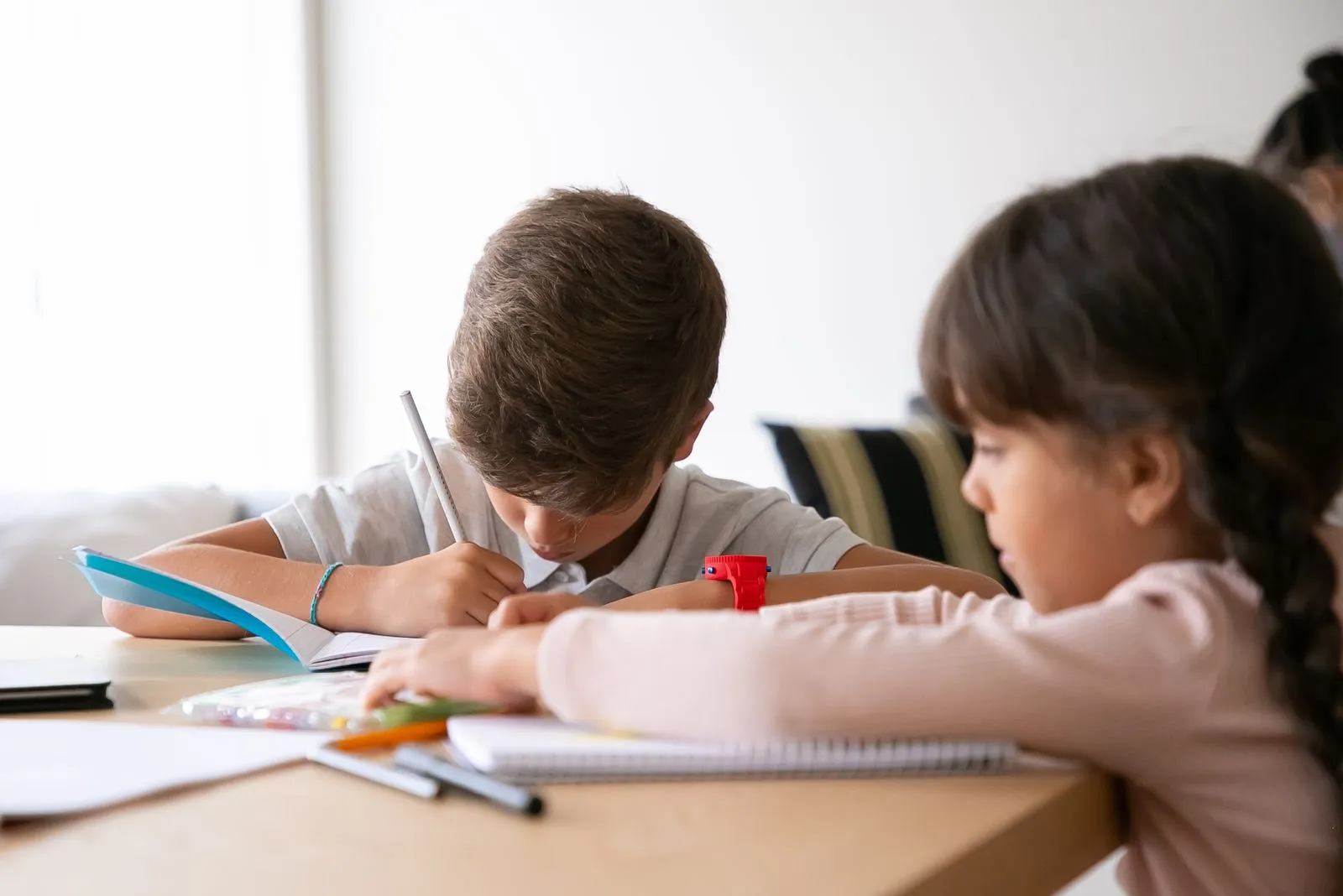 Two children studying and doing homework at a wooden table