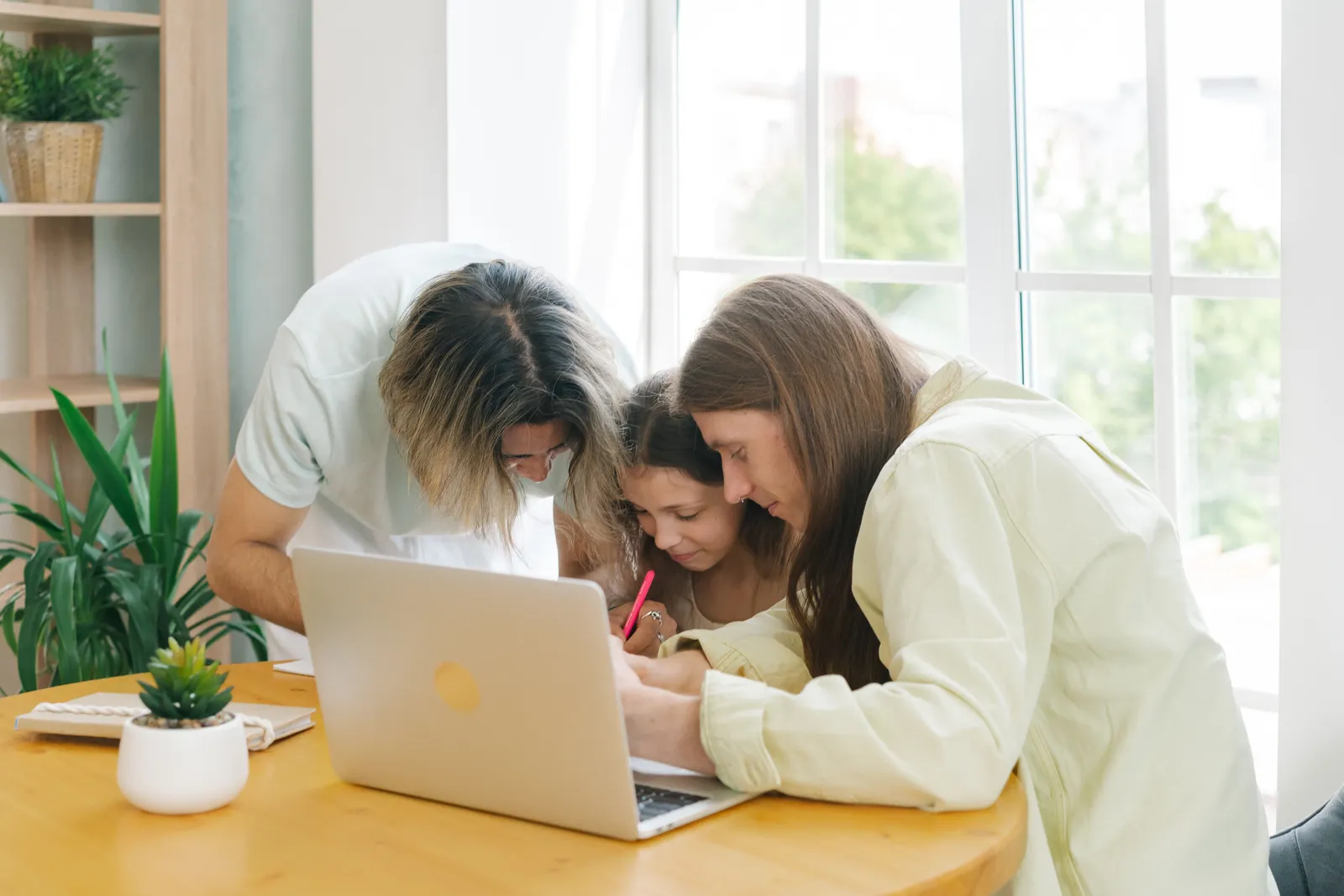 Parents sitting with their daughter and helping her study at a desk
