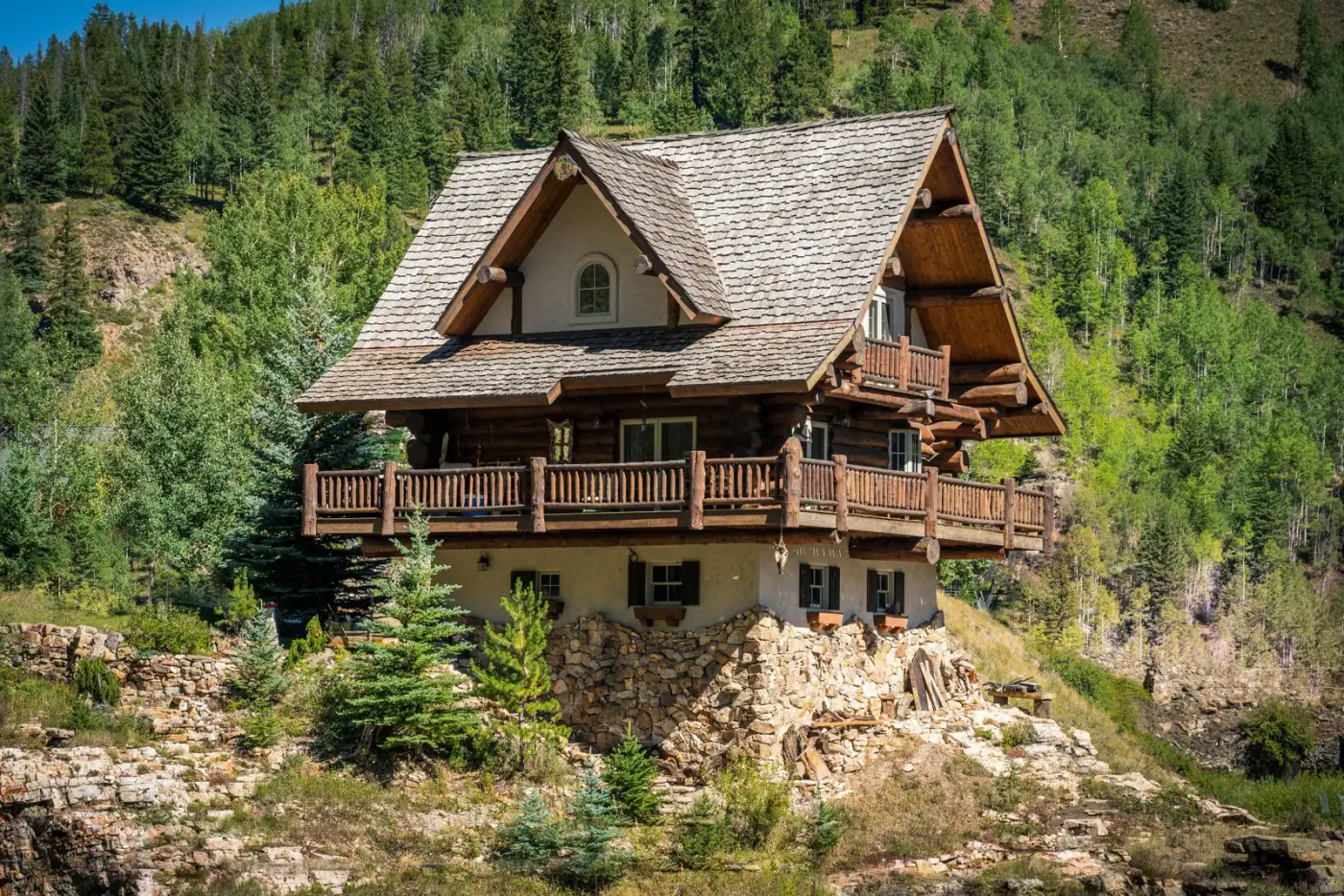 A wooden home nestled on a mountainside in Colorado surrounded by trees