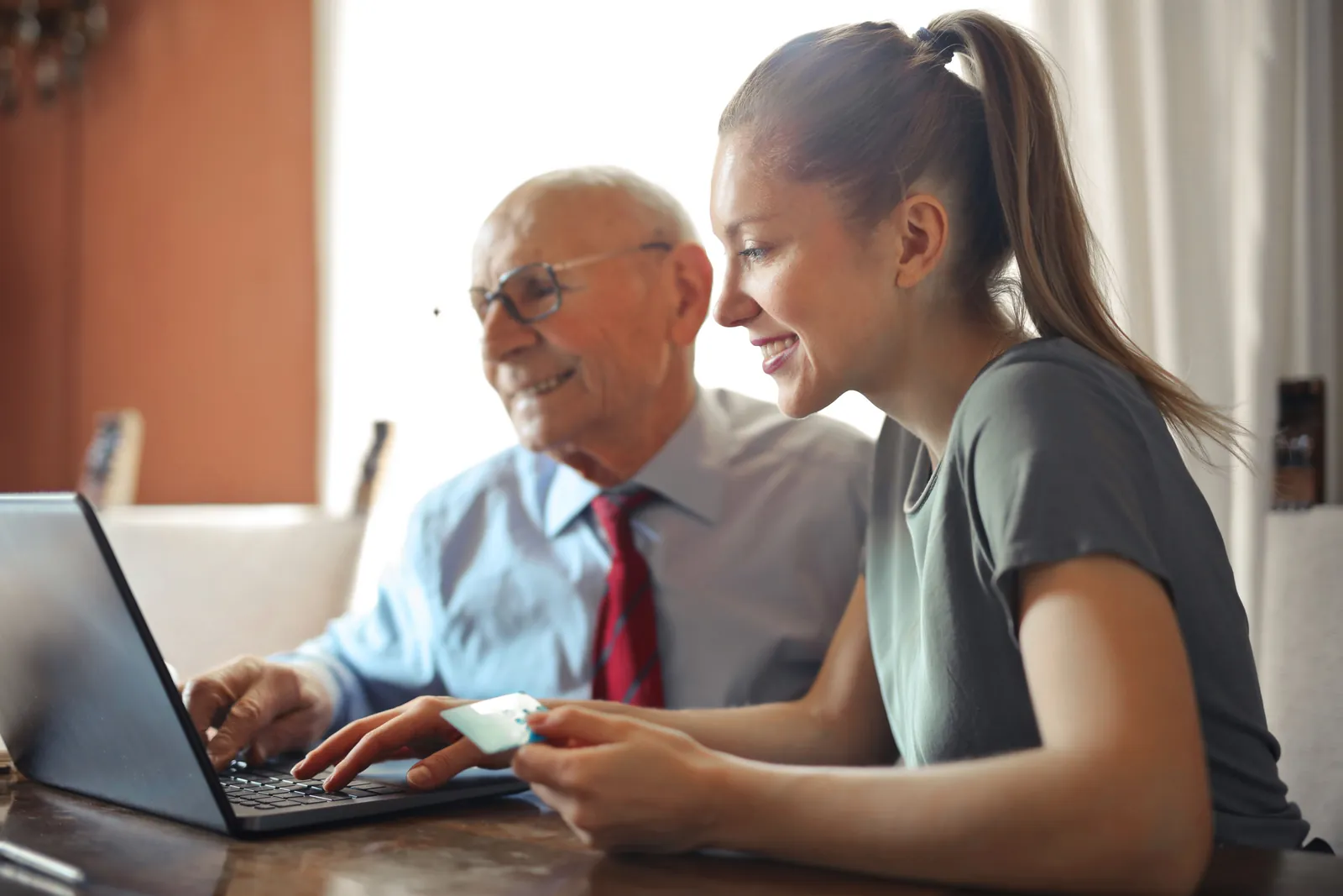 Person holding a credit card while paying online at a kitchen table