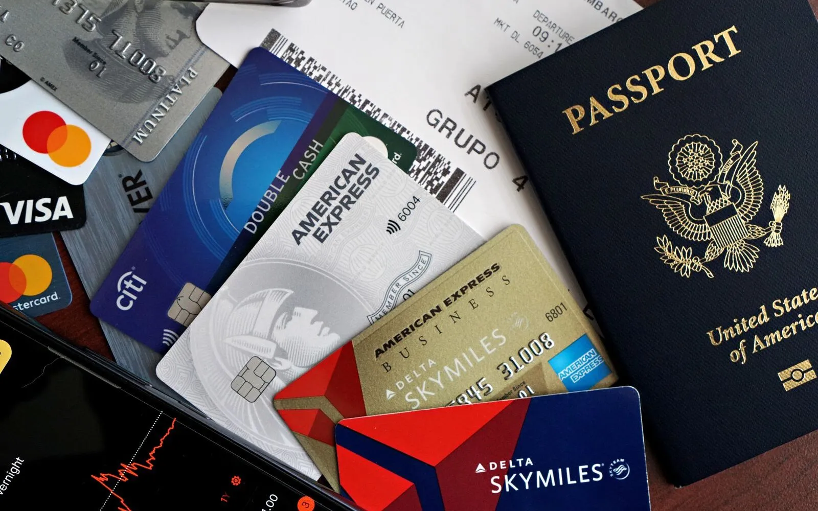 A flat lay of a passport, credit cards, and a printed boarding pass on a wooden desk