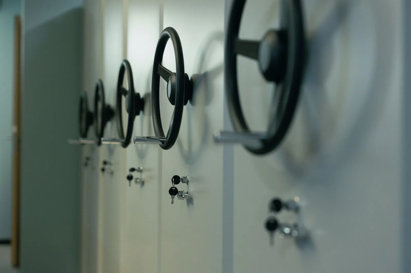 A row of steel storage cabinets with black wheel handles and keys left in their locks