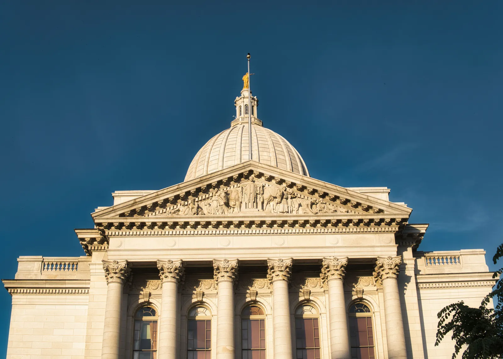 The dome and columned front of a state capitol building against a deep blue sky