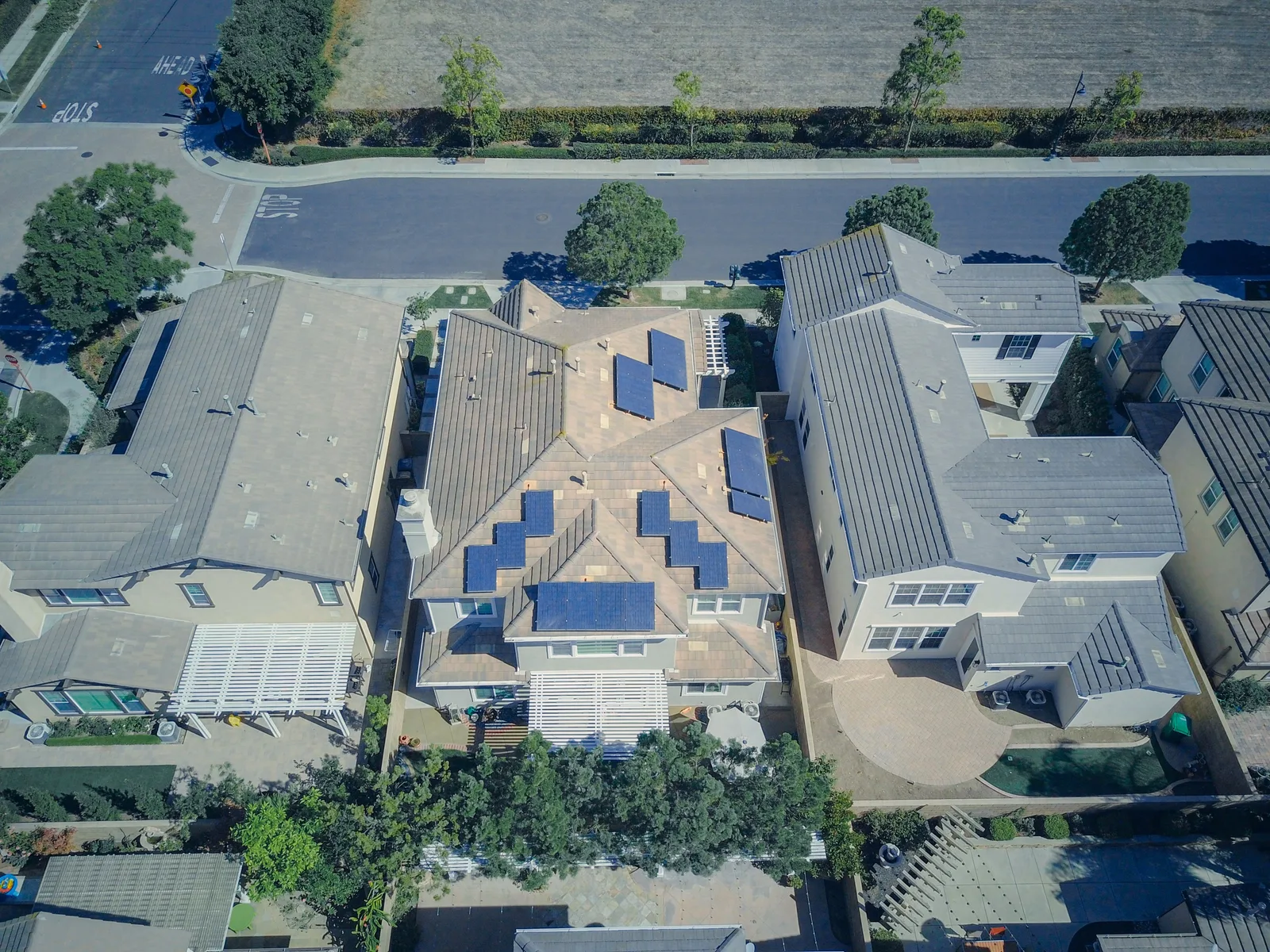Aerial view of a suburban neighborhood with solar panels on tile rooftops