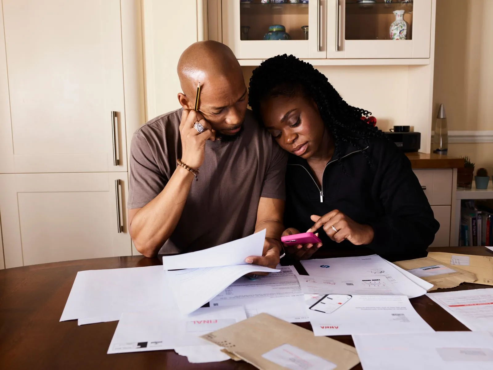 A couple at a kitchen table reviewing a bill on paper