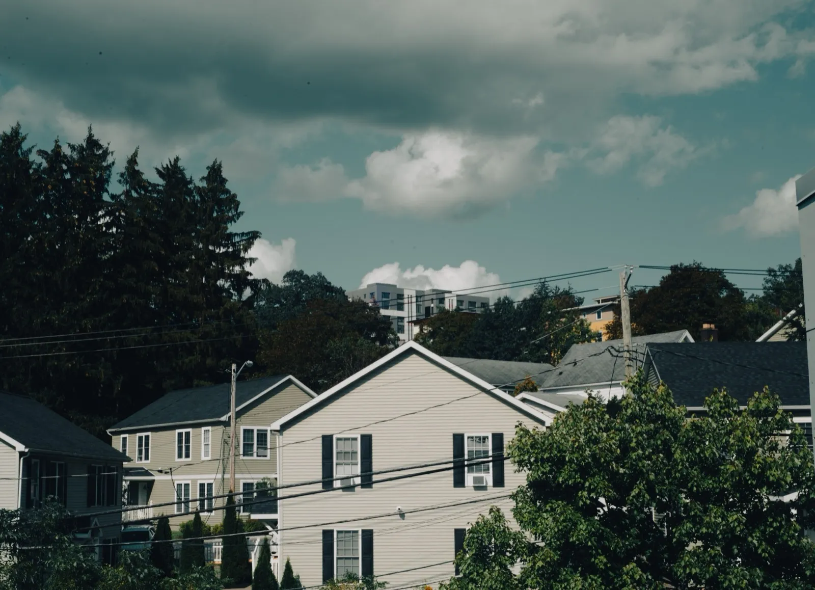 A row of suburban houses under a cloudy sky on a quiet residential street