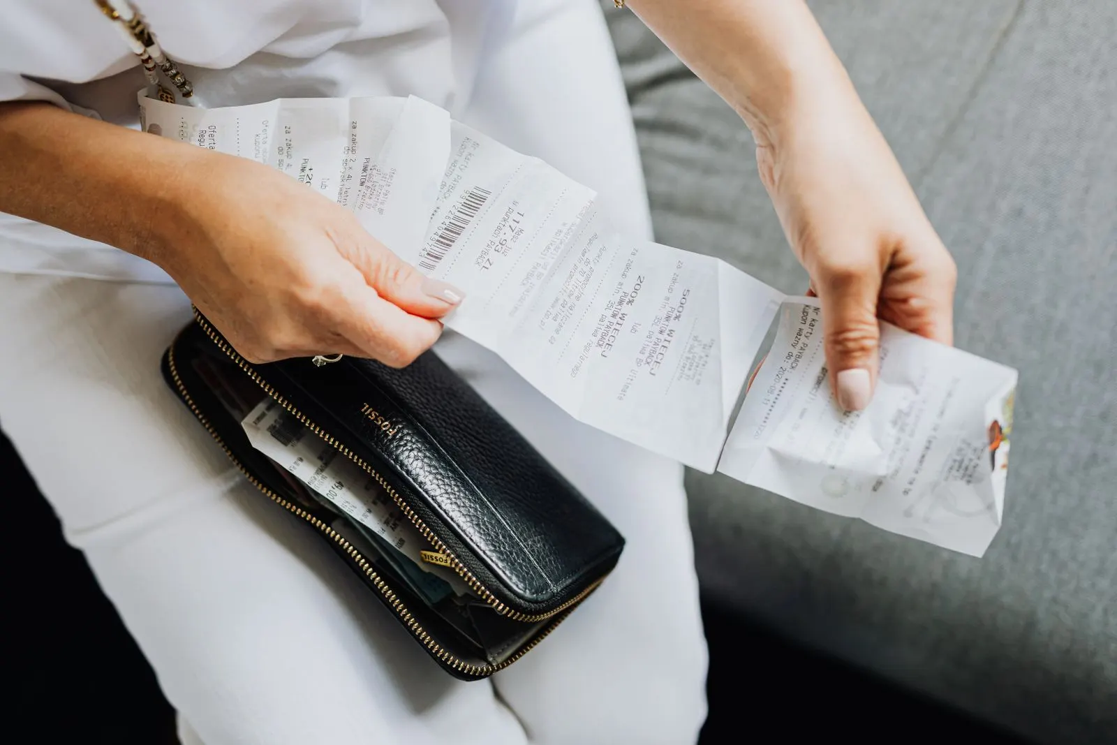 Hands sorting through paper receipts pulled from a black wallet