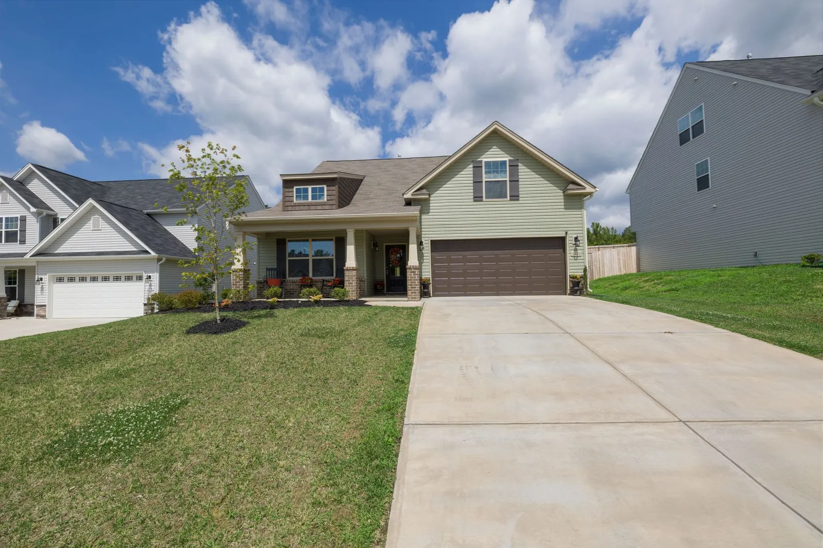 Newly built suburban house with a wide concrete driveway under a blue sky