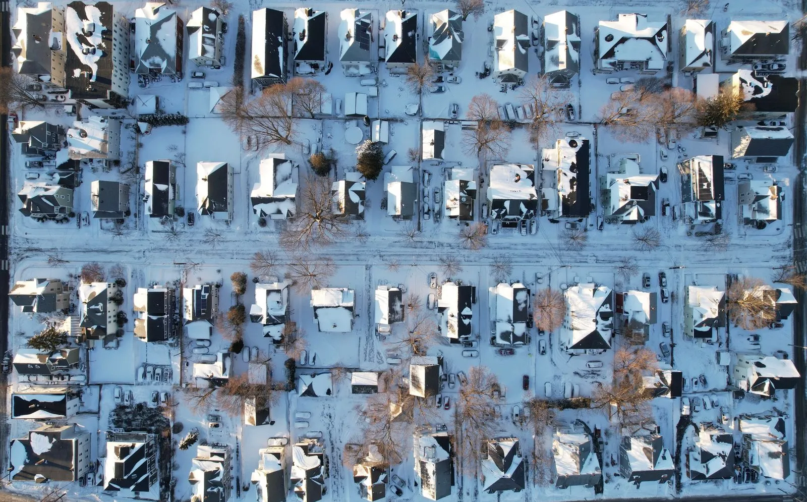 Aerial view of a snow-covered Massachusetts neighborhood, with solar panels on a few of the roofs