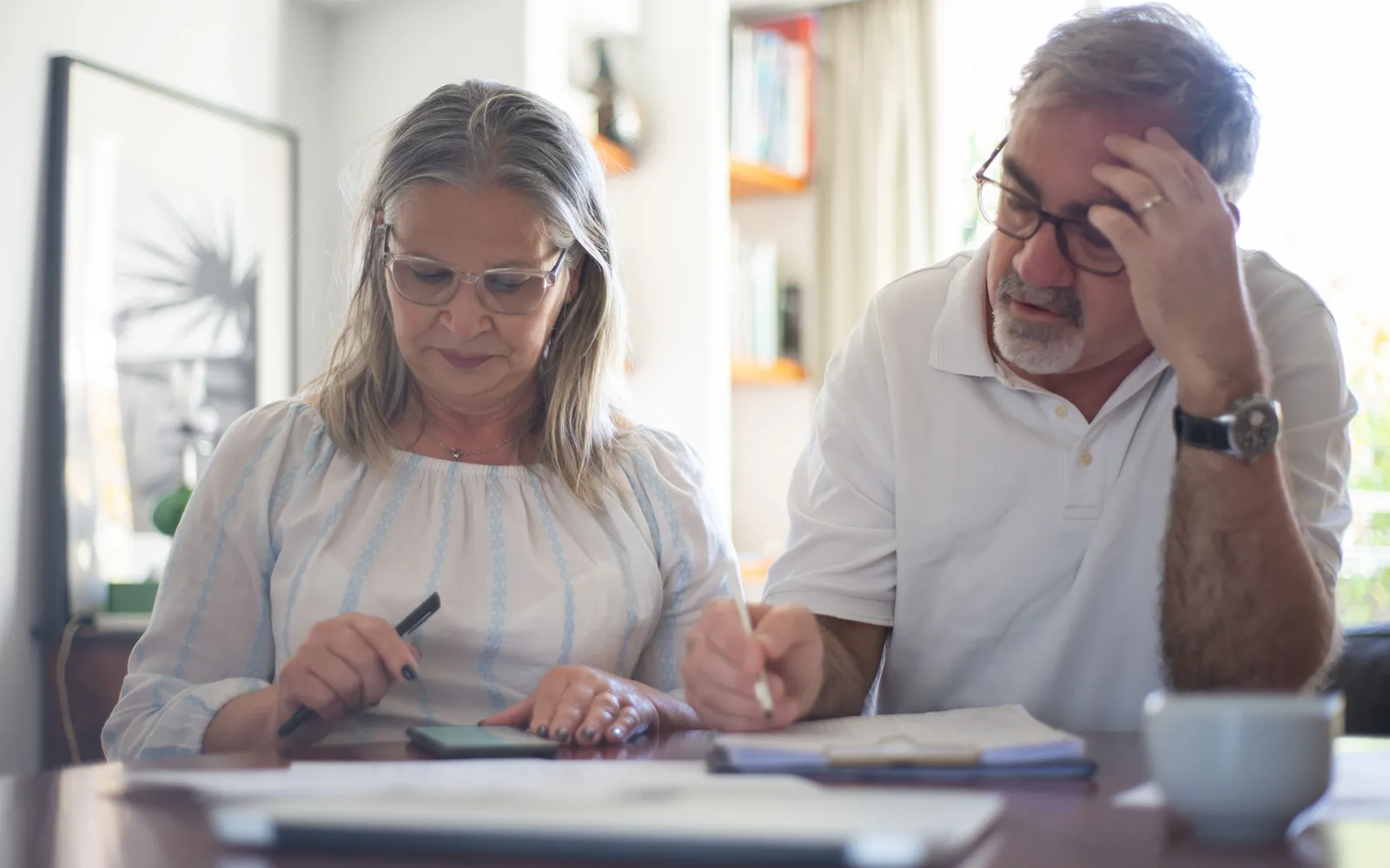 Older couple at a dining table going over household paperwork and a phone
