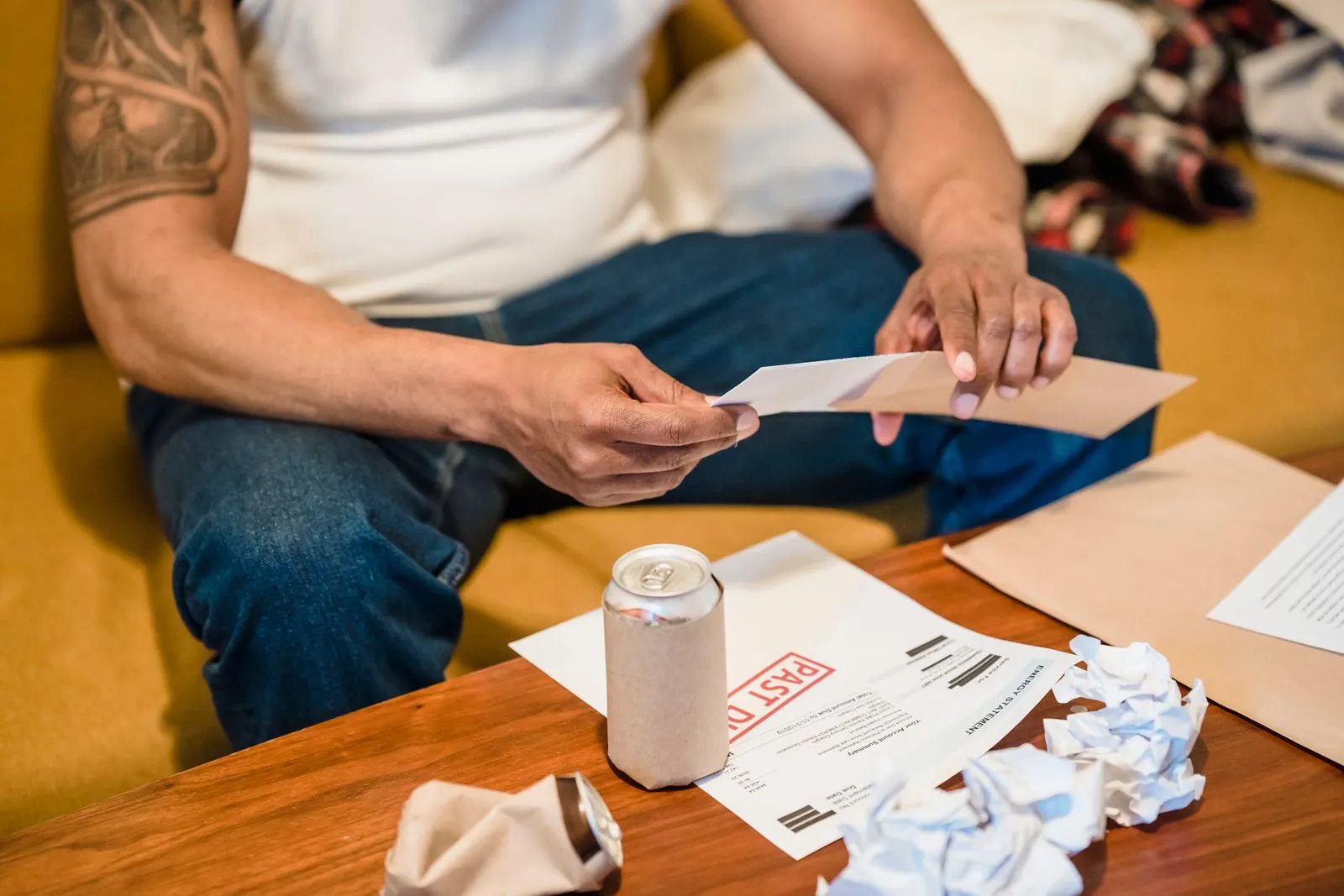 Man sitting on a couch looking through envelopes and paperwork