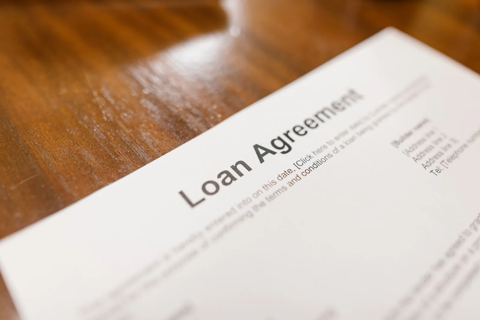 Loan agreement documents on a wooden desk with a pen resting on top