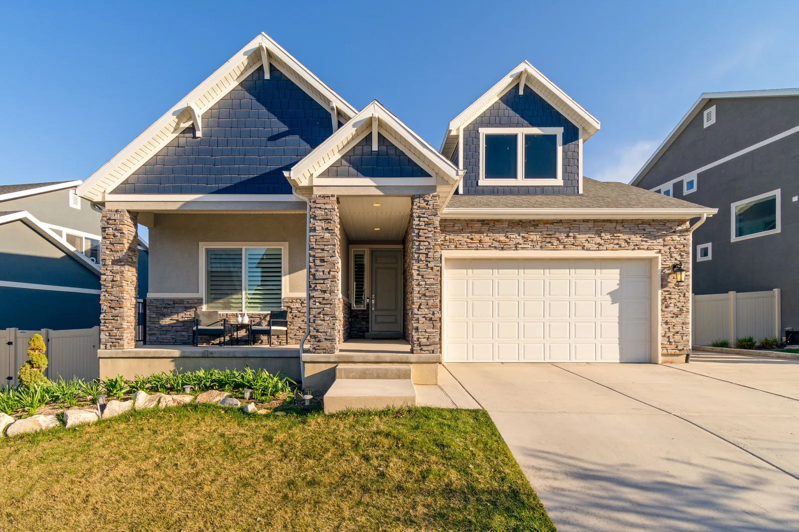 Suburban house with a stone facade, white garage door and a trimmed front lawn