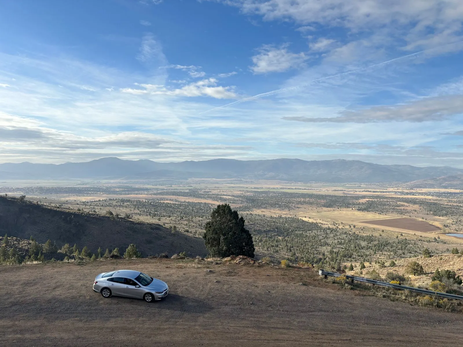 Silver car parked at a Nevada desert overlook with valley views in the distance