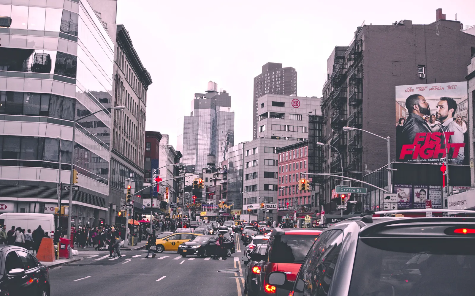 Traffic and yellow taxis moving down a busy New York City street on a clear day