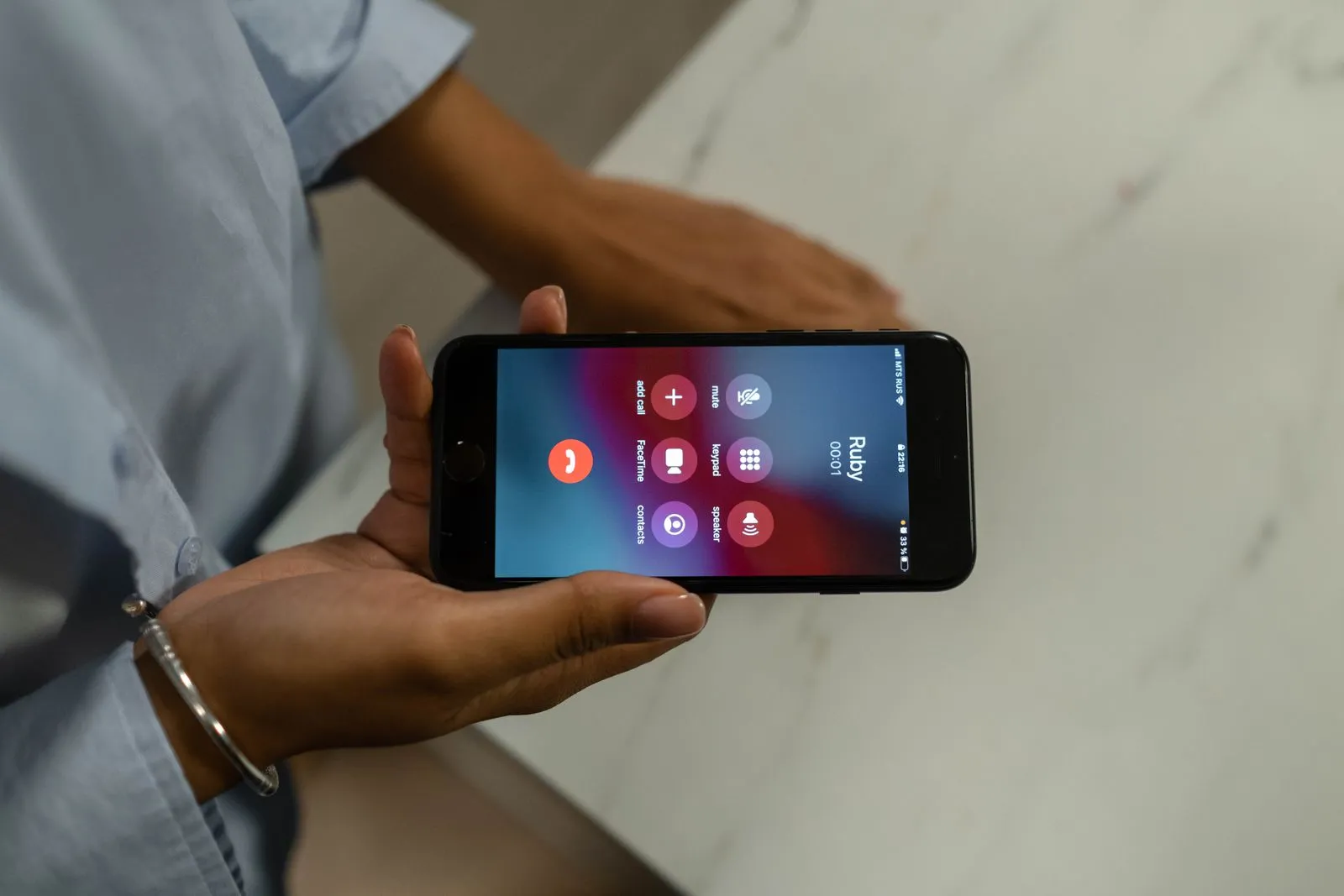 Close-up of a hand holding a smartphone showing an incoming call on the screen