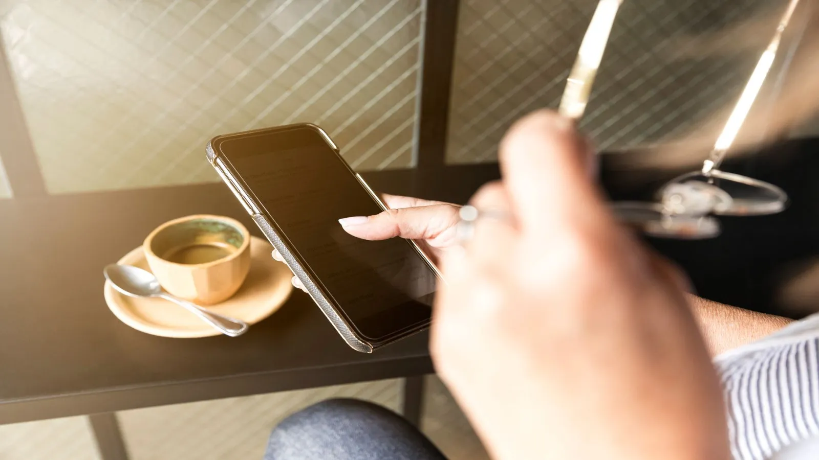 Young person checking a phone banking app on a couch with a coffee mug