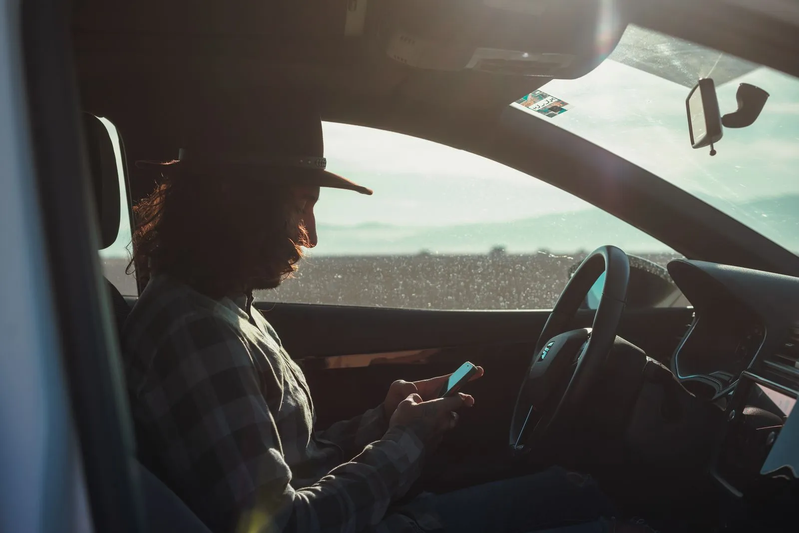 Driver checking auto insurance quotes on a phone in a parked car