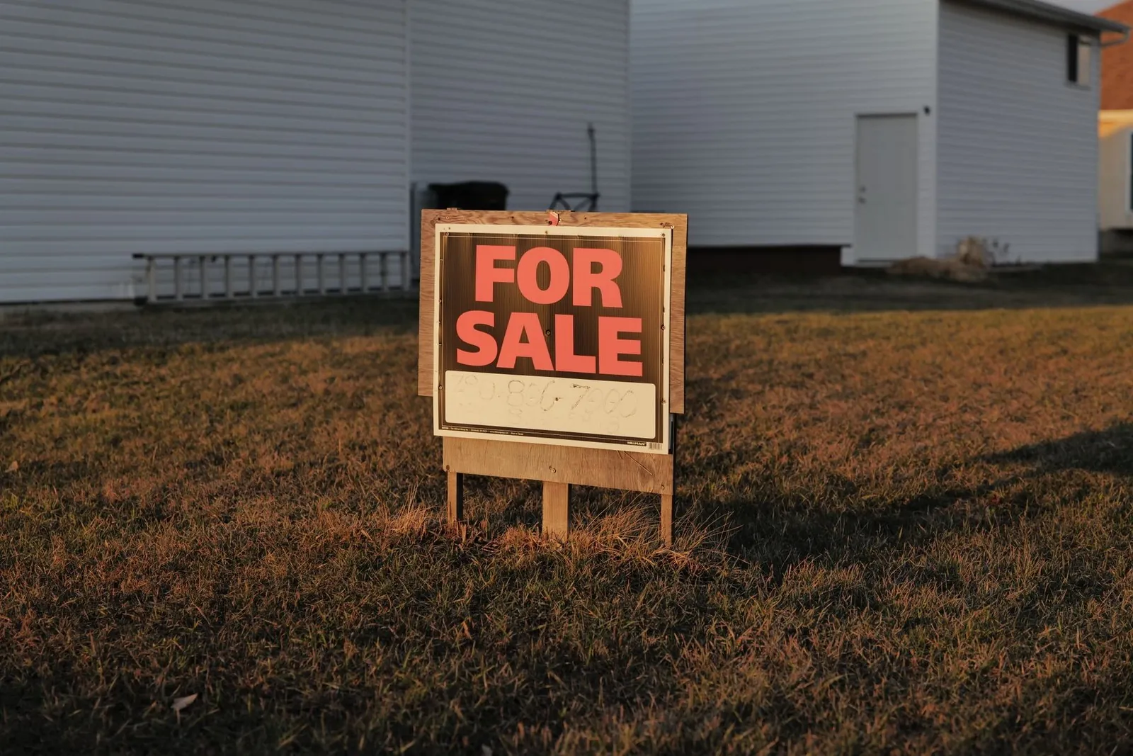 Suburban houses on a residential street with a for sale sign in the foreground