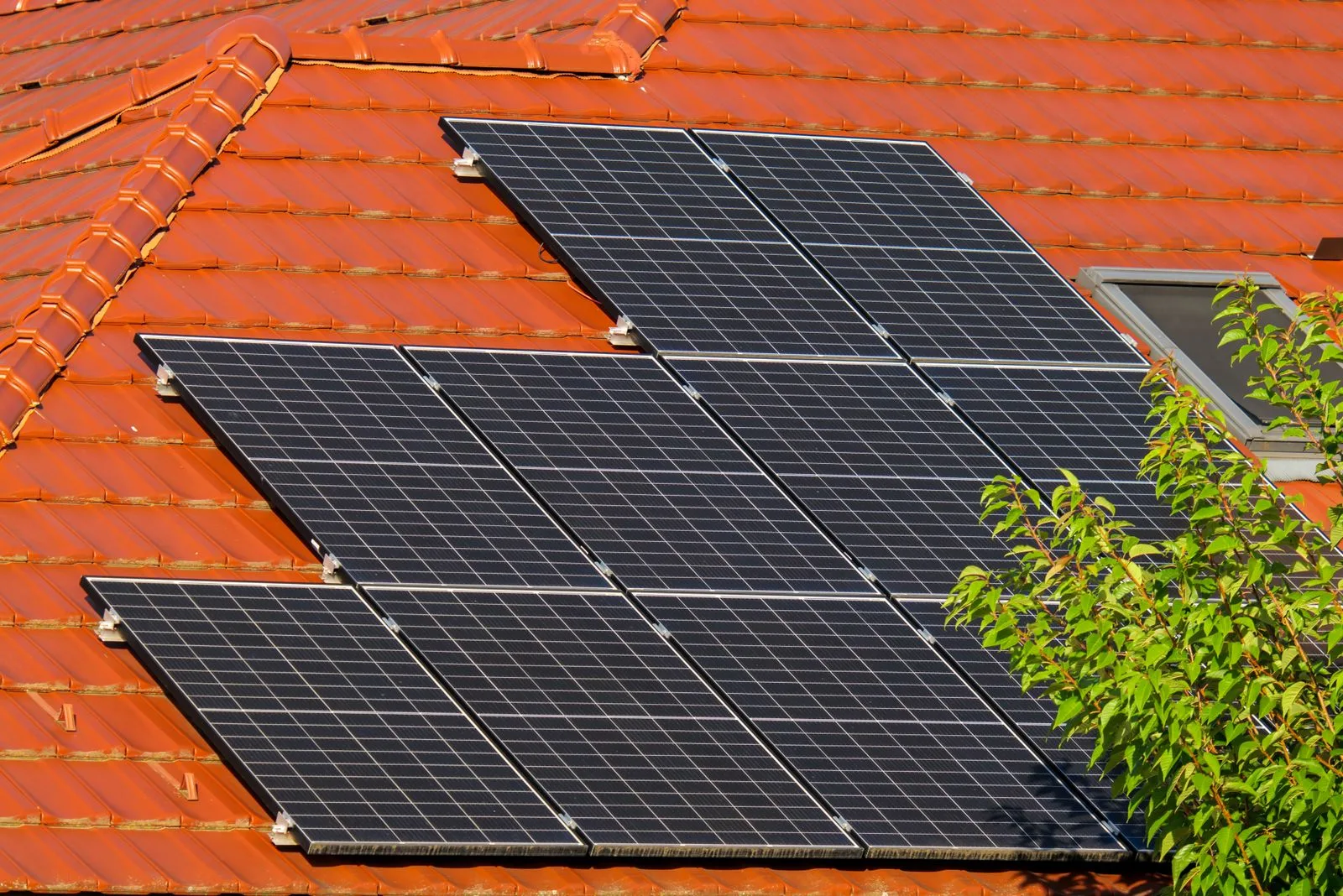 Solar panels mounted on the tiled roof of a house under a clear sky