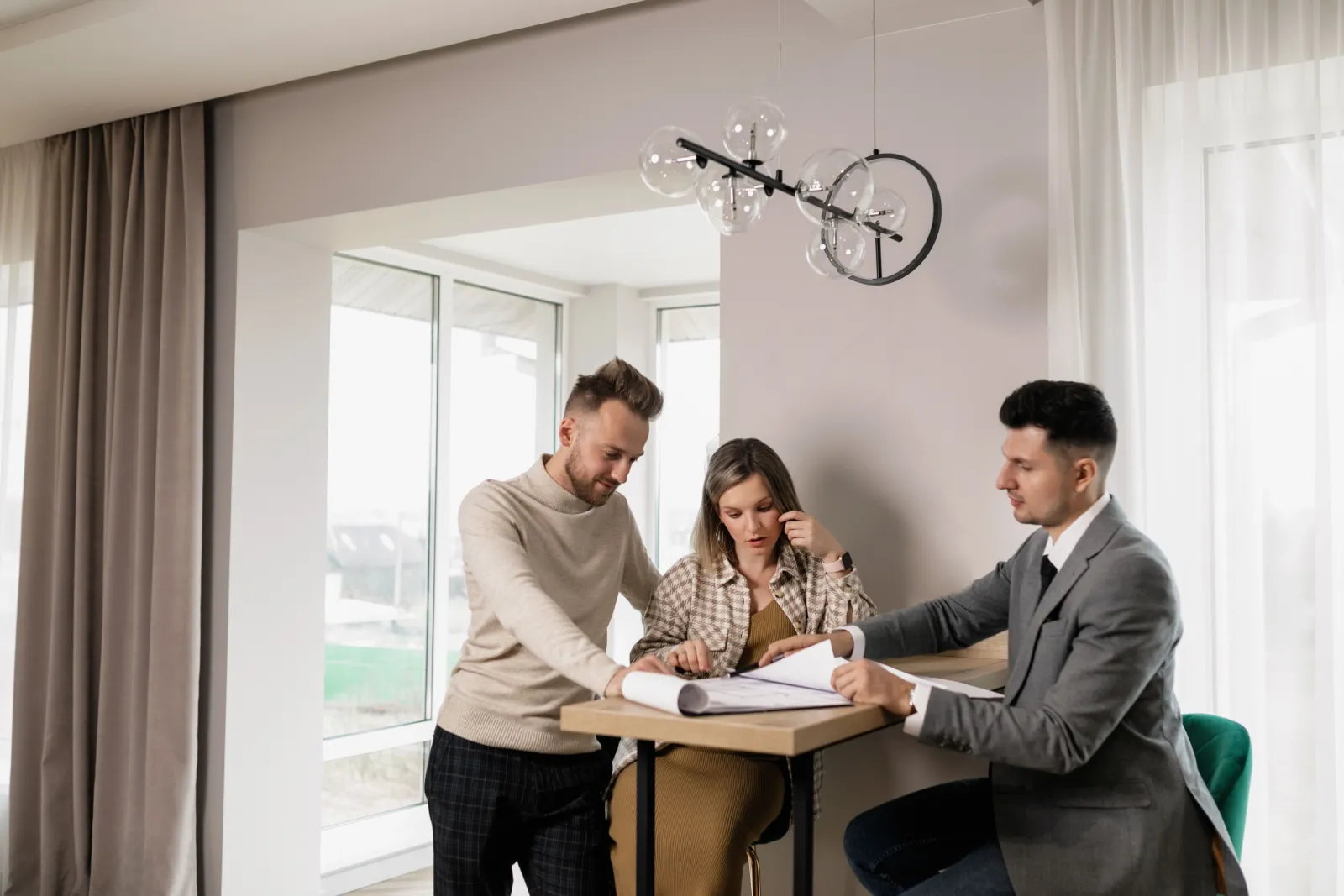 A couple looking over contract paperwork with a salesperson at a table in their home