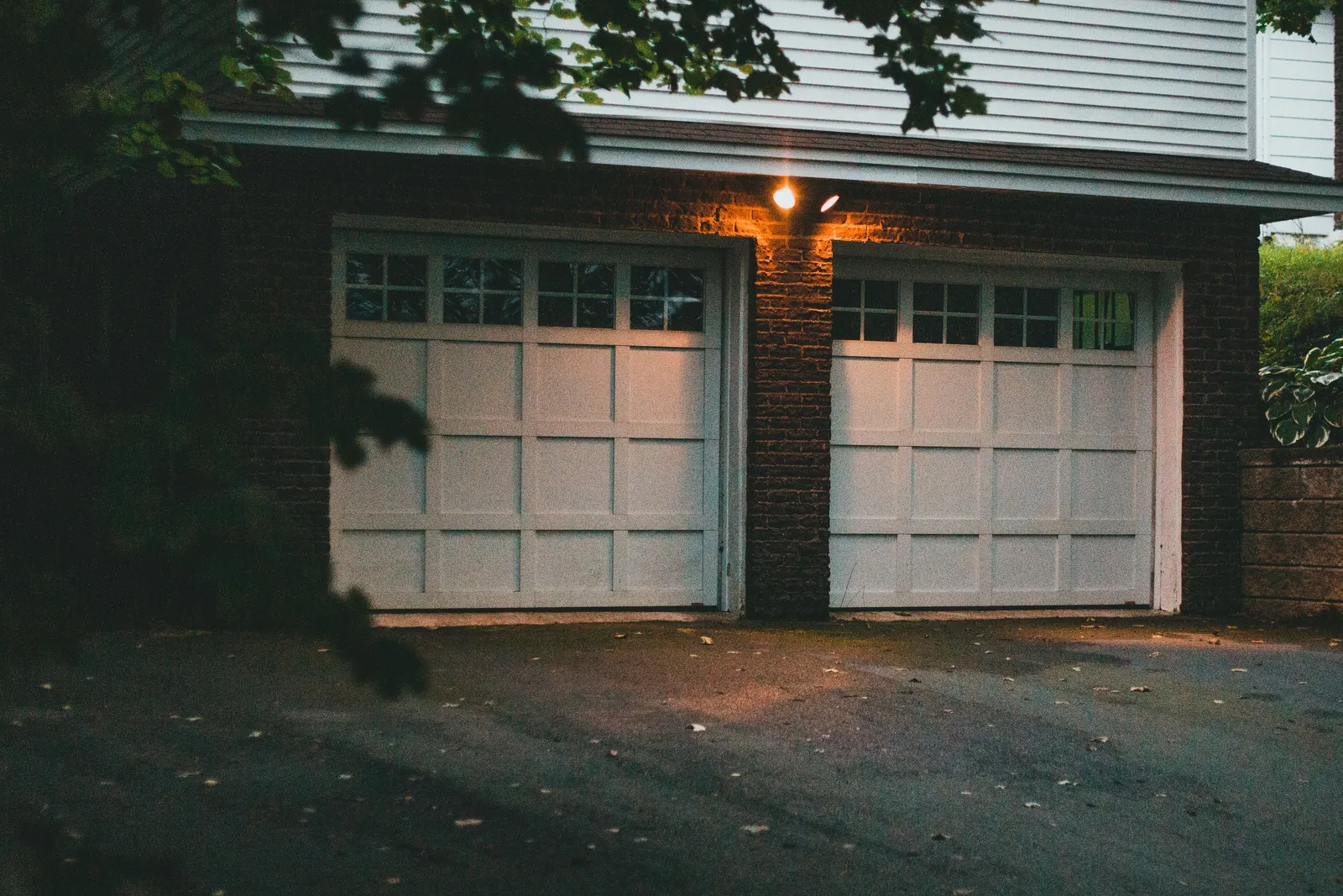 Two-car garage at dusk with a single light on above the closed doors