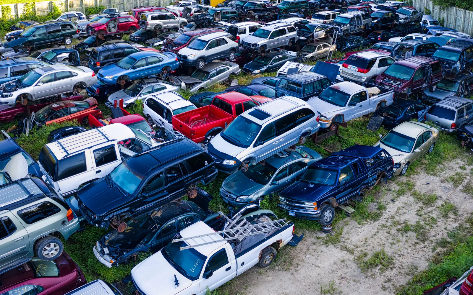 Aerial view of rows of damaged vehicles parked in a fenced storage yard