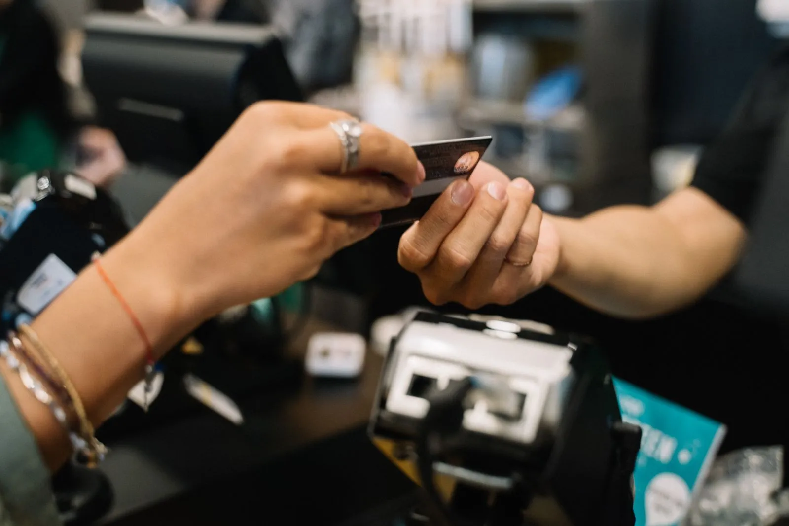 Person handing a credit card to a cashier at a small retail counter