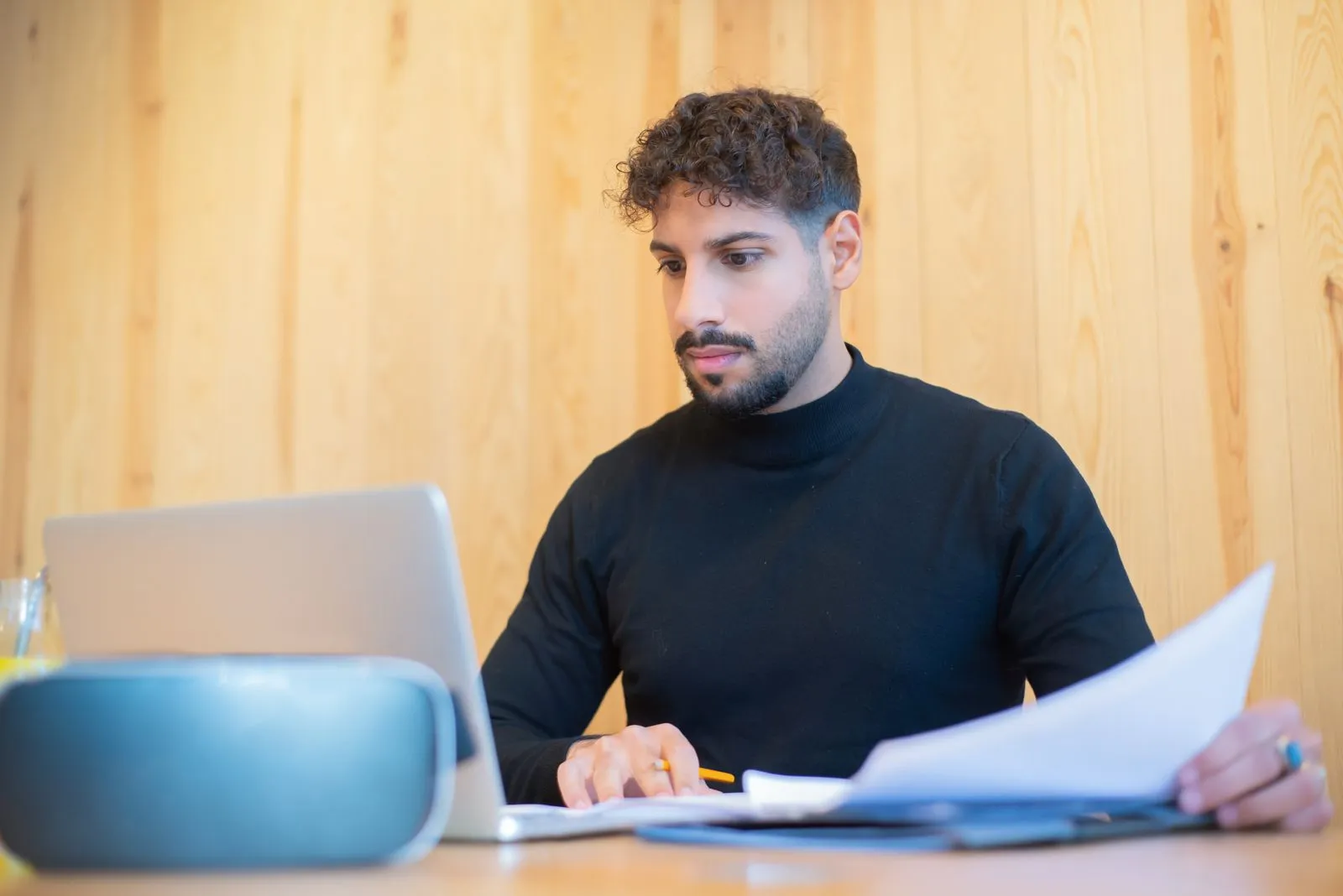A man at a kitchen table reviewing mortgage paperwork on a laptop