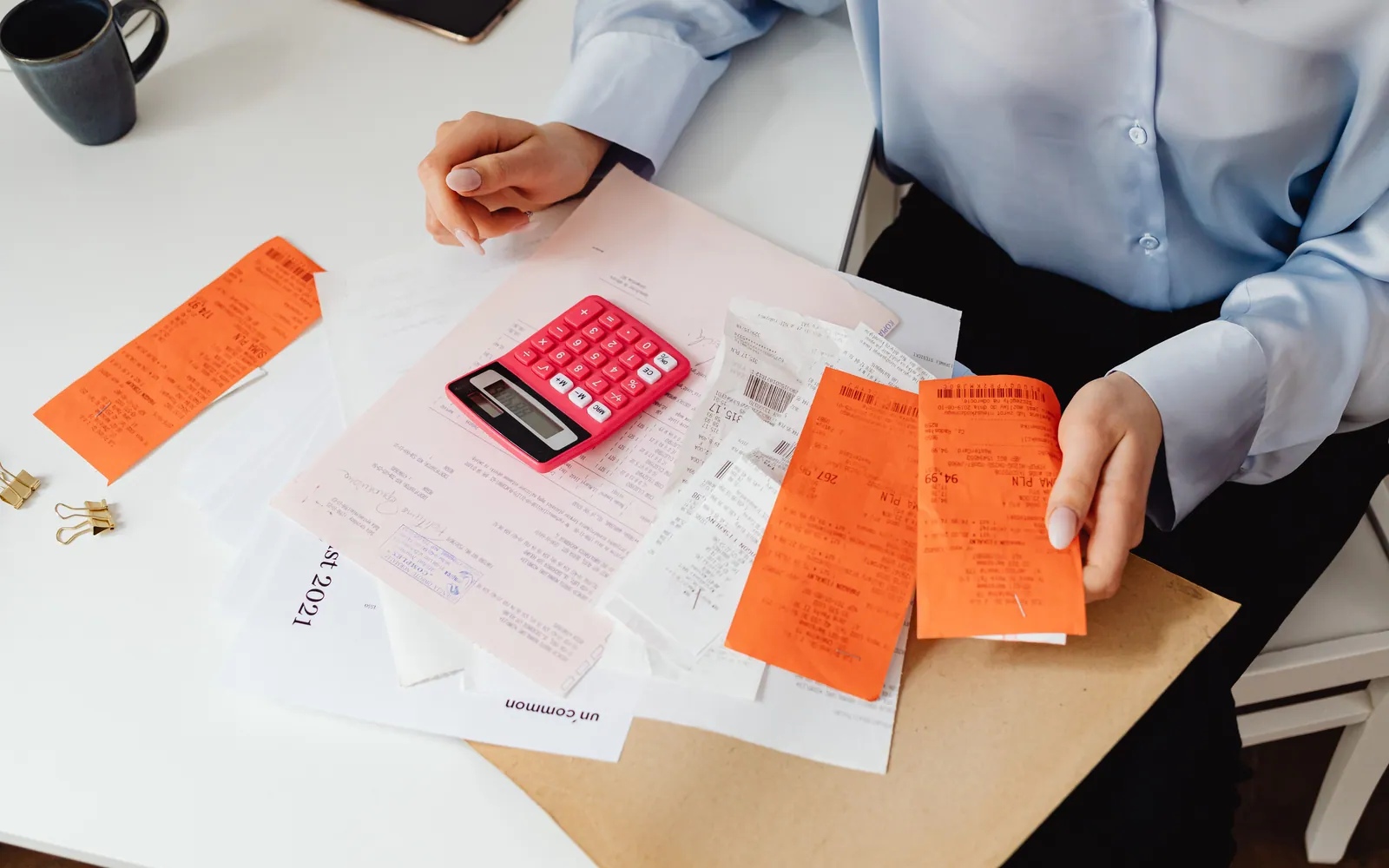 Person organizing bills with a calculator
