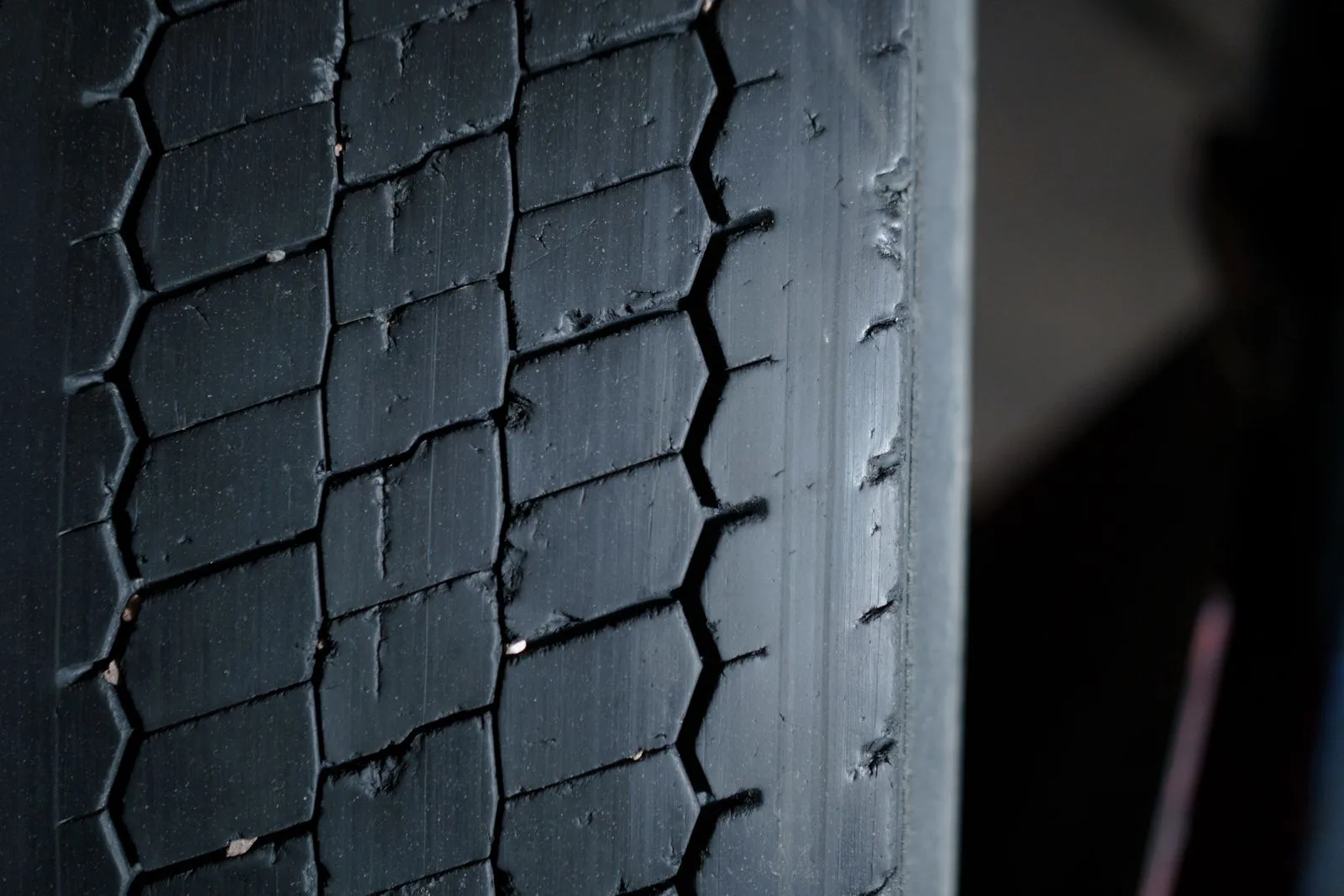 A close-up of a worn tire tread with small stones caught between the blocks